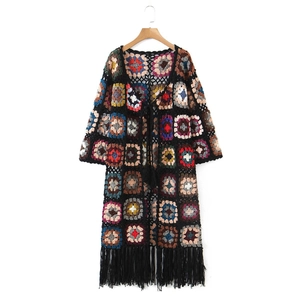 Detailed view of handmade granny square crochet cardigan with colorful fringe hem