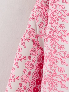 Close-up of white quilted fabric with detailed pink floral line art pattern on the coat