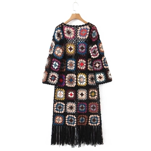 Detail of colorful crochet patchwork patterns and long fringe tassels on the black cardigan