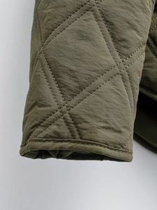 Detailed macro view of olive green diamond quilted stitching on the jacket sleeve cuffs