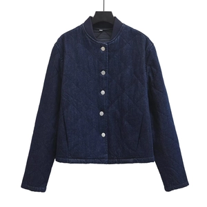 Detail of diamond quilted texture and silver snap buttons on dark blue denim jacket