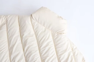 Close-up of quilted cream winter jacket featuring high collar and fine stitching detail