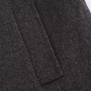 Detailed close-up of stitching on dark grey wool coat pocket showcasing fabric texture