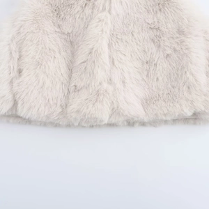 Close-up of soft faux fur texture on a cream sleeveless vest with long fluffy fibers