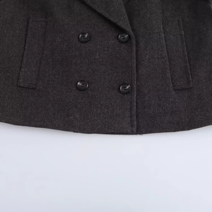 Detail of dark grey double-breasted coat featuring round black buttons and textured wool fabric
