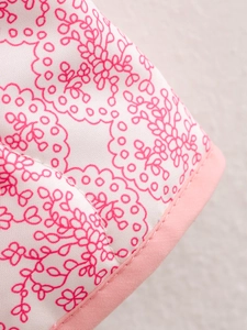 Detailed macro view of the pink floral pattern and precise stitching on the cotton jacket
