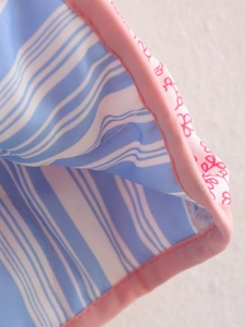 Macro view of pink floral print jacket with blue striped lining and neat stitching