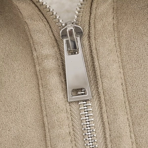 Dettaglio della cerniera metallica e della fodera in sherpa sulla giacca color beige