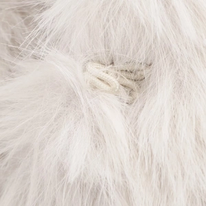 Close-up of white faux fur texture featuring a woven loop fastener detail on the vest