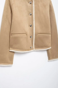 Detail of camel suede jacket featuring white shearling-like trim and silver metal buttons