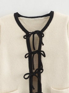 Cream knit cardigan with contrasting black bow ties and refined round neck detailing