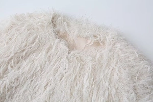 Detail of soft cream faux fur jacket with fluffy fringe texture and metal trim neckline