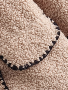 Gros plan sur la texture sherpa beige avec des surpiqûres décoratives noires élégantes
