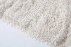 Macro view of creamy white faux fur fabric with fringe textures and fluffy material details