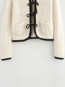Chic cream knit cardigan featuring black trim and velvet bow ties for a street style look