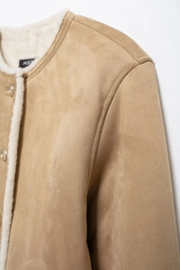Detail of camel suede jacket with white faux shearling lining and metal buttons