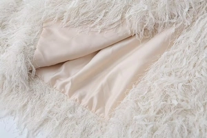 Detailed macro view of white faux fur fringe and smooth satin lining on the jacket