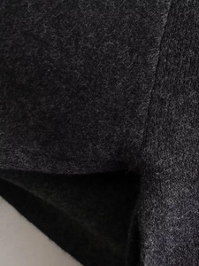 Macro detail of charcoal grey wool blend knit fabric showing soft texture and premium stitching