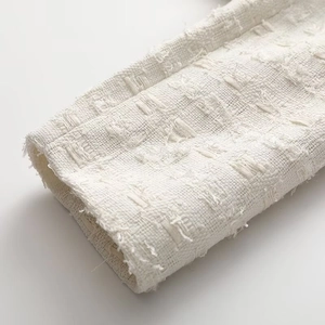 Gros plan d'un poignet de veste en tweed blanc avec ourlet à franges et texture détaillée