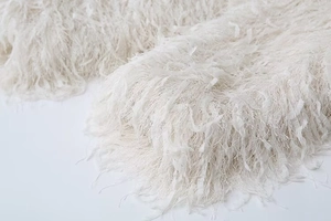 Macro detail of white faux fur jacket featuring plush tassel texture and soft fringe
