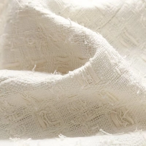 Gros plan sur le tissu en tweed crème montrant la texture tissée et les détails frangés
