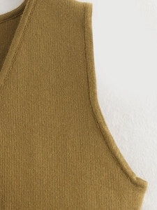 Detailed view of the rib-knit mustard yellow vest featuring precise shoulder seam stitching