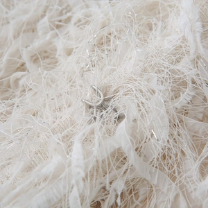 Macro shot of polished silver metal ring mount with four-prong setting on feather background