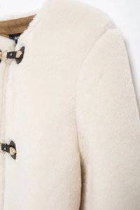 Close-up of faux fur texture with elegant leather buckle and metal fastener on jacket