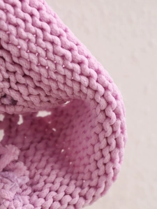 Macro shot of soft lavender pink knit texture on a button-up round neck cardigan