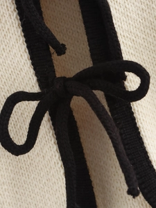 Detailed macro view of cream knitted fabric texture with a black bow ribbon tie accent