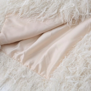 Detailed macro view of light beige satin fabric with soft white faux fur fringe detail