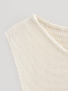 Vue macro du gilet en maille blanc crème montrant les coutures et la texture du tissu