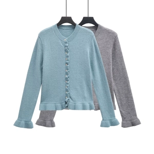 Detailed close-up of ruffle trim edges on two stylish knit cardigans in grey and blue