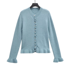 Close-up of light blue knit cardigan with ruffle trim details and button-down front