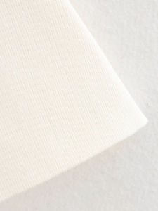 Macro texture du tissu en maille plate fine et détail de l'ourlet côtelé en blanc crème