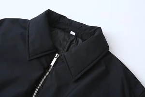 Gros plan du col de veste noir avec revers classique et détail de fermeture éclair argentée