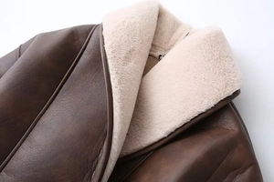 Detail of premium brown leather exterior and thick cream faux fur lining on winter coat