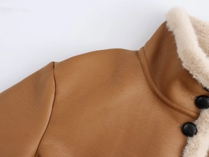 Gros plan sur une veste en cuir marron avec col en peau lainée crème et bouton noir texturé