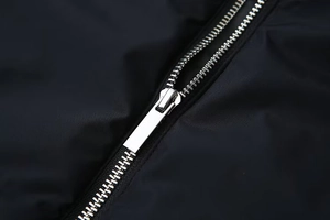 Détail macro d'une fermeture éclair en métal argenté sur une veste légère noire