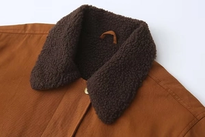 Détail d'une veste en sergé marron avec col en polaire sherpa et bouton doré