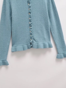 Close-up of teal knit cardigan with ruffle trim details and single-breasted buttons