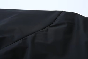 Détail de la couture industrielle sur une veste matelassée noire légère pour femme