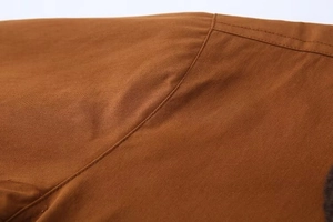 Détail des coutures renforcées et de la texture sergé sur la veste marron