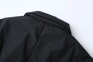 Détail du col à revers noir et du tissu coupe-vent sur cette veste courte élégante