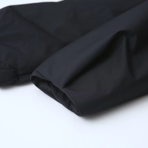 Vue détaillée du tissu noir mat et des poignets coupe-vent d'une veste en coton légère