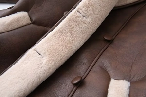 Detail of dark brown faux leather jacket with cream fur lining and round button