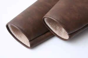 Detailed close-up of dark brown PU leather jacket cuff with thick white faux fur lining