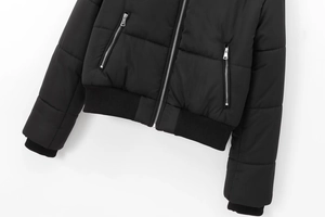 Detail of black puffer jacket showing silver zipper pockets and ribbed windproof cuffs