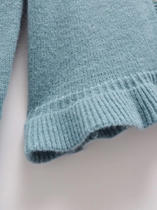 Detailed macro view of the greyish blue knitted cardigan sleeve with ribbed cuffs