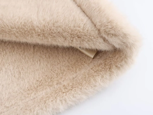 Gros plan sur le tissu doux en laine d'agneau synthétique beige pour veste d'hiver
